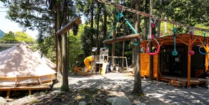 Explore the resort's outdoor play area, featuring a playhouse with a slide, a wooden deck, and a swing set.