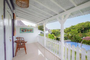 A covered balcony with a white railing, a wooden chair, and a table. - The Kleep Jungle Resort (Penida Island)