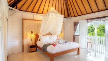 A bedroom with a wooden bed, white bedding, a canopy, and a balcony with a white fence.