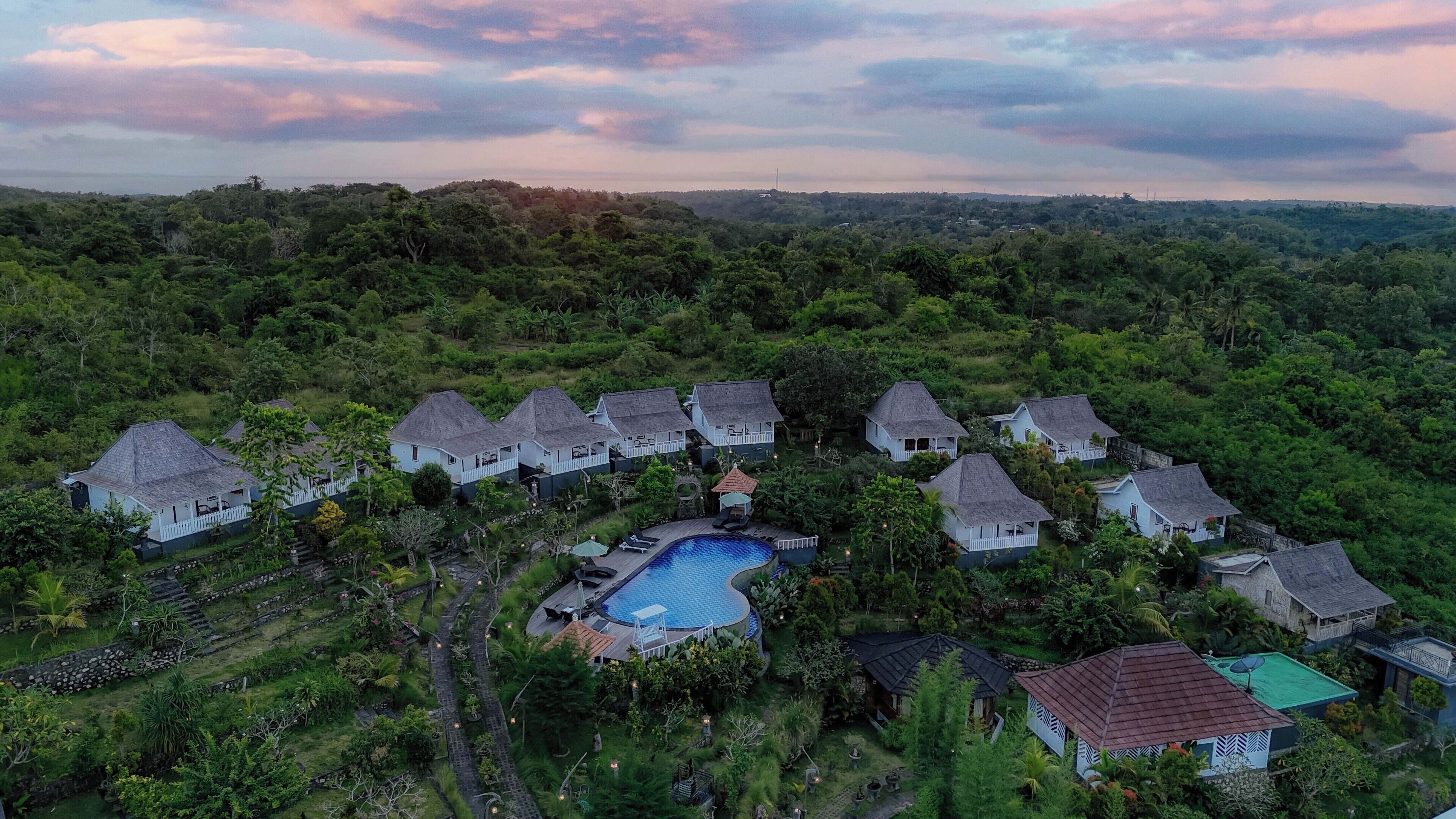 A resort with multiple bungalow-style accommodations, a central swimming pool, and lush surrounding vegetation.