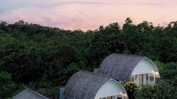 A cluster of dome-shaped cottages surrounded by dense forest, each with a porch and exterior lighting.