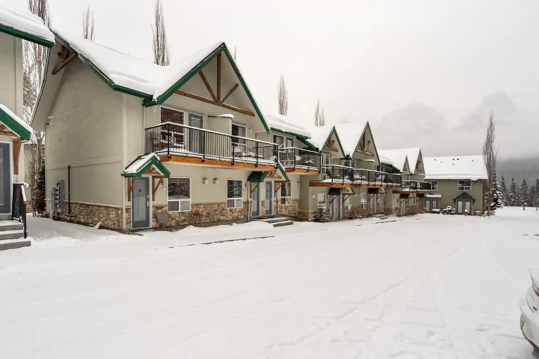A row of chalet-style buildings with balconies, set in a snowy landscape.