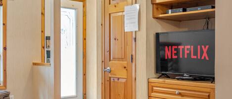 A cozy room with wooden furniture, a television displaying 'NETFLIX', and a wooden cabinet.