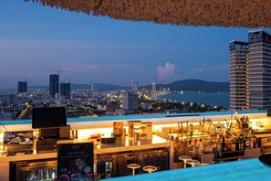 A rooftop bar with a city view, bar equipment, and a menu board. - L'amor Boutique Hotel Quy Nhon (Quy Nhon Nam)