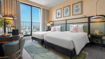 Habitación de hotel con dos camas, un escritorio y vistas a la ciudad.