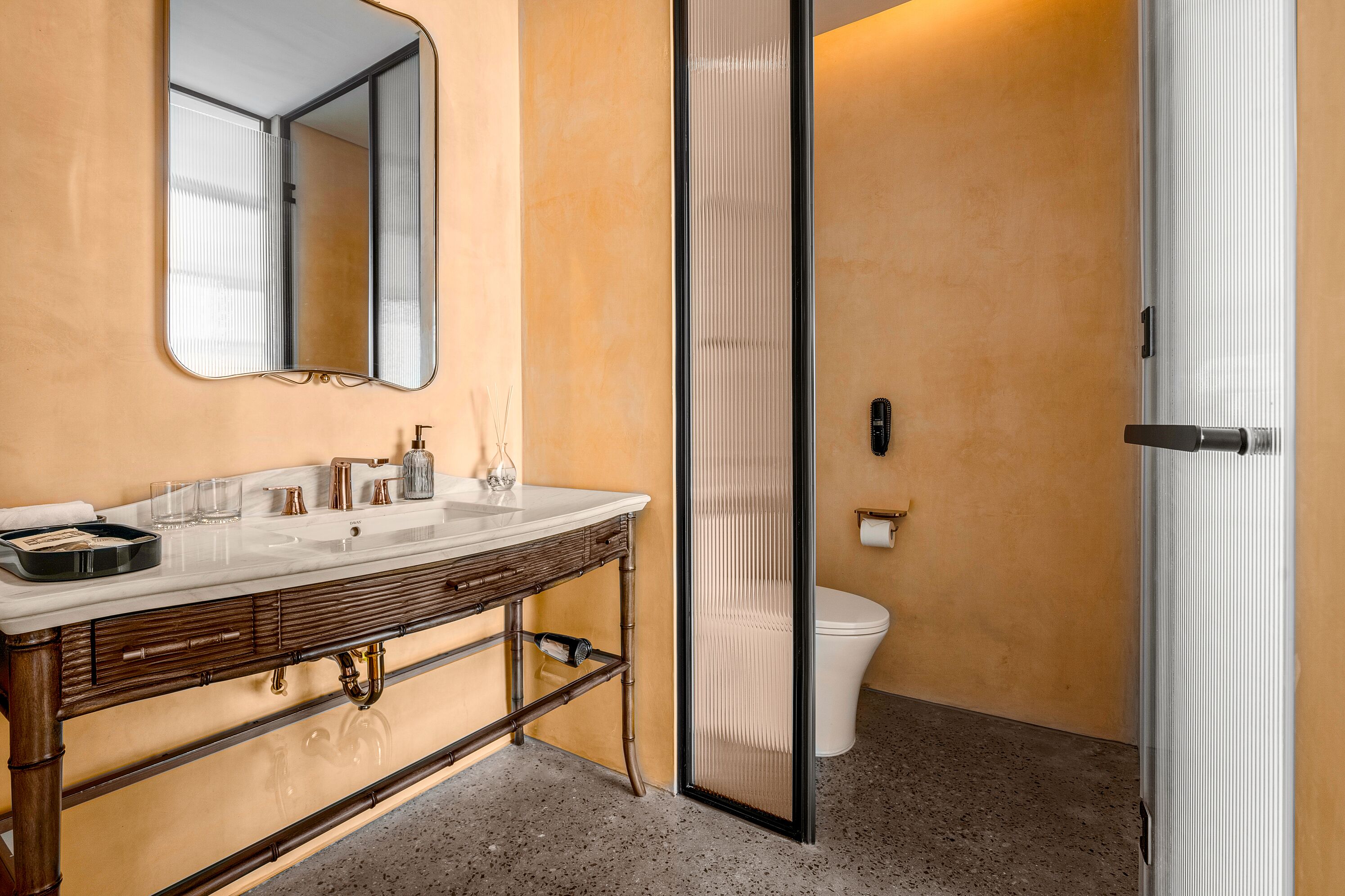 Een badkamer met een wastafel, wasbak, spiegel en toilet.