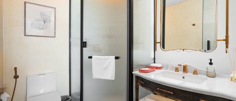 A modern bathroom with a toilet, shower, sink, and a large mirror.