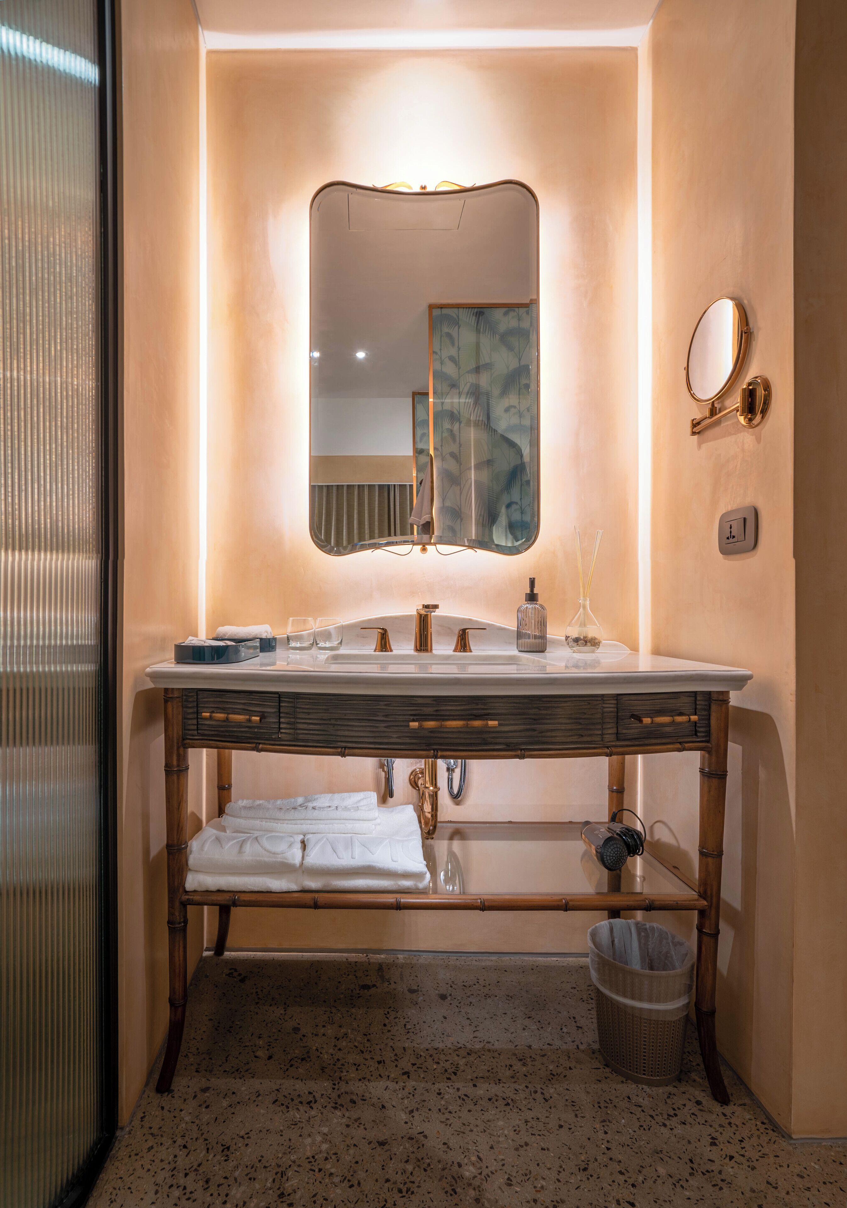 Un baño con lavamanos de mármol, un espejo grande y un mueble de tocador de madera.