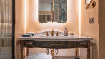 Un baño con lavamanos de mármol, un espejo grande y un mueble de tocador de madera.
