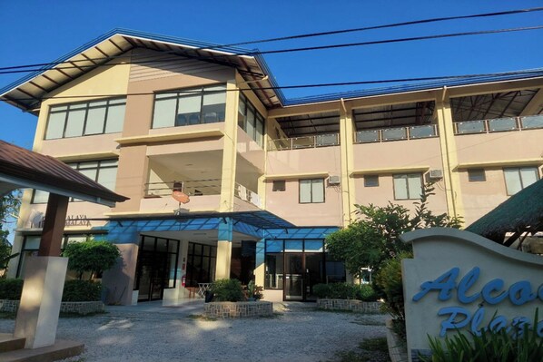 A multi-story hotel with a modern design, featuring a prominent entrance with a covered area and a sign that reads "Alcoa Plaza". - Alcoy Plaza Eco Park Cebu (Alcoy)