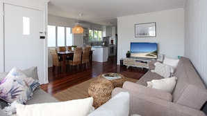A modern living room with a large sofa, a television, and a dining area with a table and chairs.
