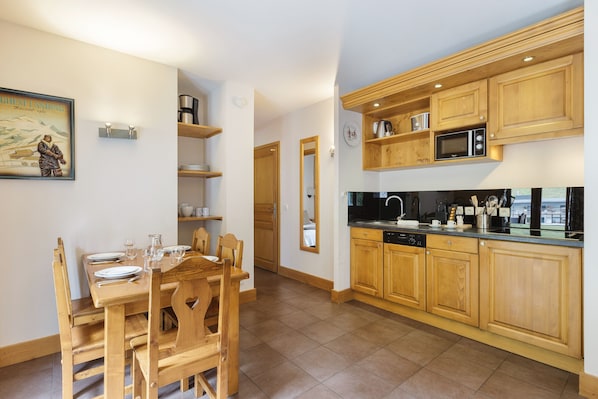 Cocina moderna con armarios de madera, zona de comedor con mesa dispuesta para cuatro y una isla de cocina.