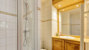 A bathroom with a glass-enclosed shower, a white toilet, wooden cabinets, and a sink with a mirror above it. - V Buet 42: Beside Ski Lift; Pool, Sauna & Gym, Vallorcine (Argentiere), France (Vallorcine (Argentiere))