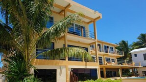 A multi-story hotel with balconies, a pool, and palm trees. - Club Rooms At Popeyes Beach Resort (Caye Caulker)