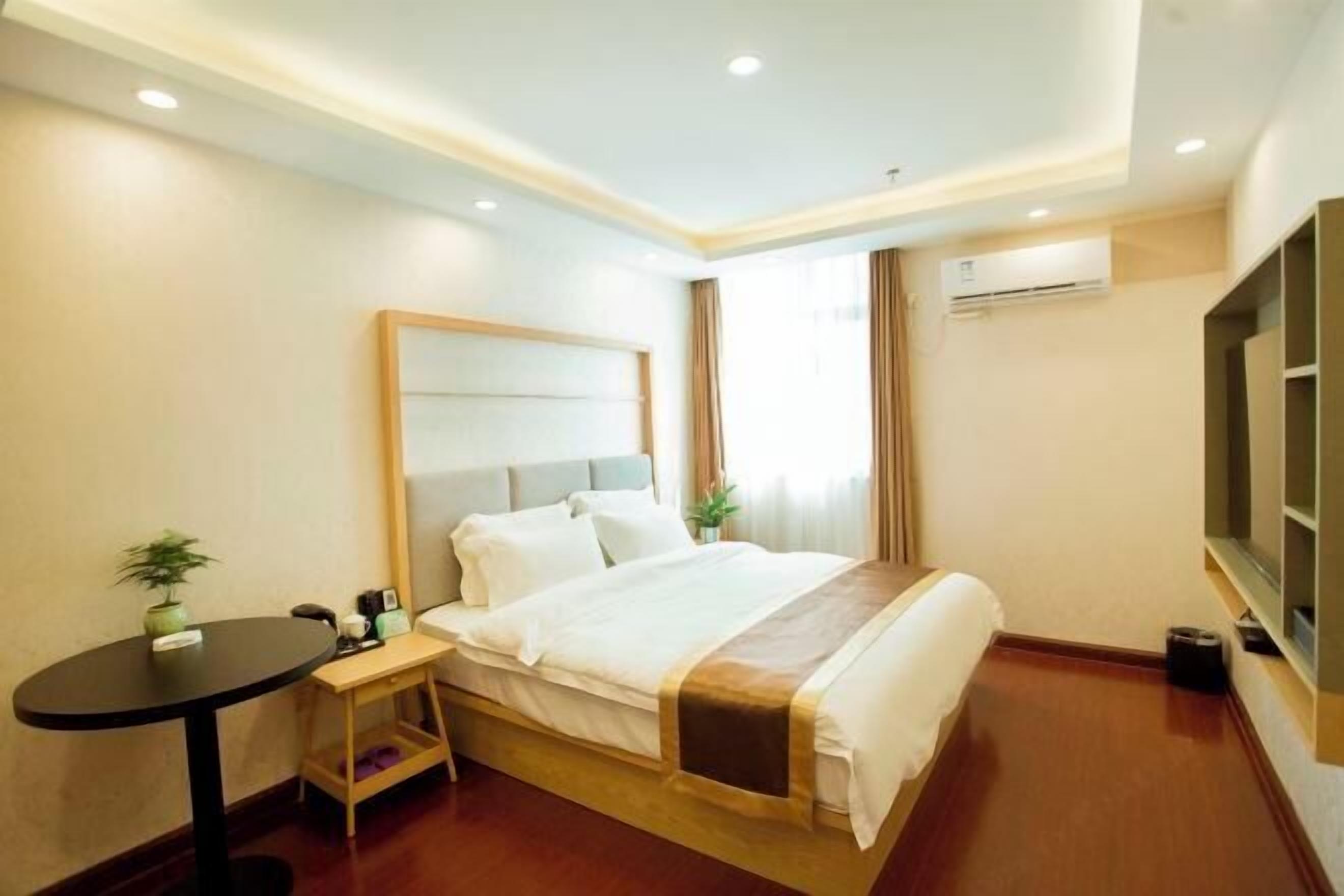 A hotel room with a bed, bedside table, lamp, and a TV.
