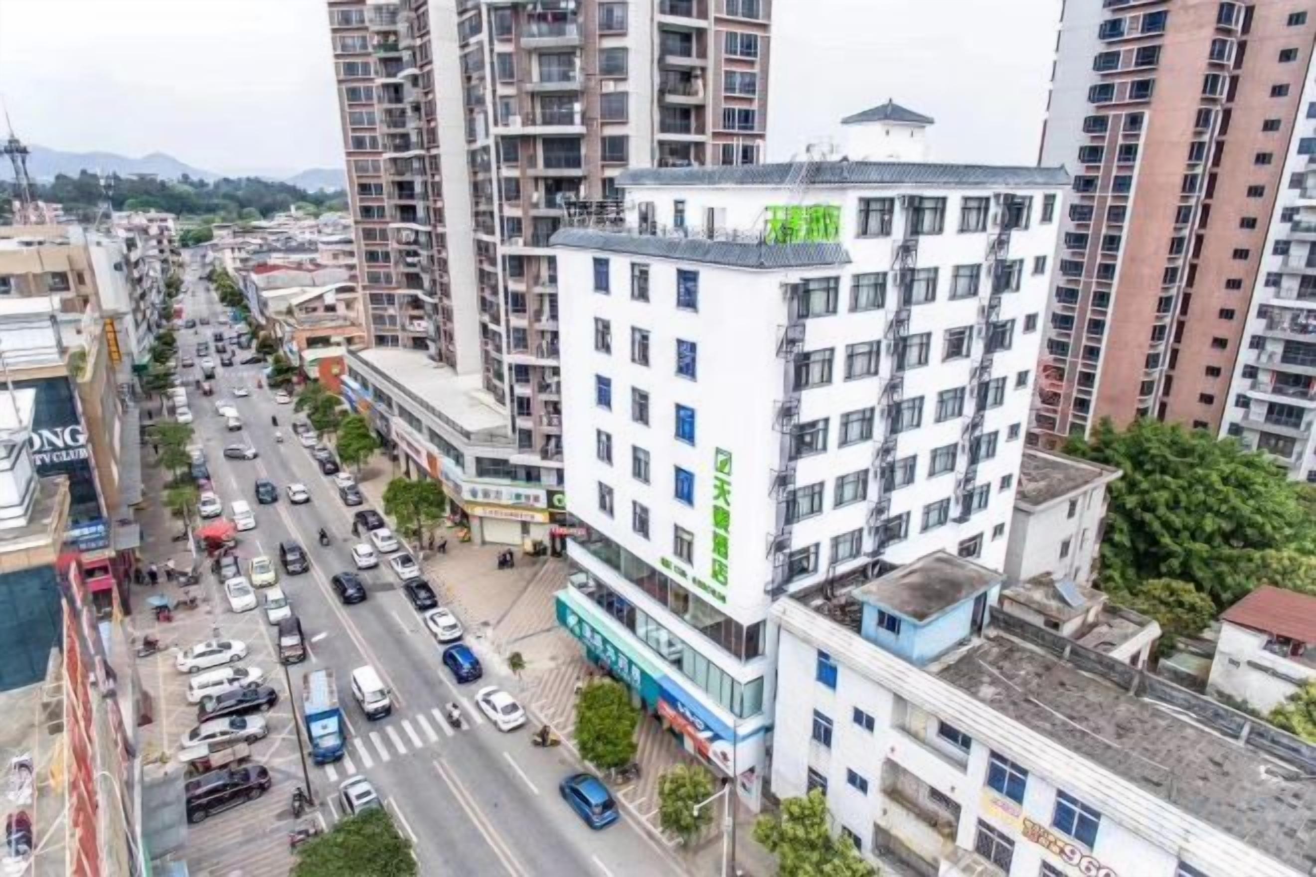 Edifício de vários andares com um térreo comercial, rodeado por uma rua movimentada com veículos e pedestres.