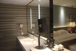 A modern hotel room with a large bed, a bedside table with a coffee maker, a mirror, and a wall-mounted phone. - Insail Hotels Loufu Mountain Branch (Boluo)