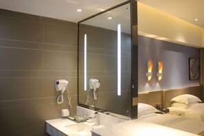 A hotel room with a large mirror, a bed with white linens, a bedside table, and a wall-mounted hairdryer. - Insail Hotels Loufu Mountain Branch (Boluo)