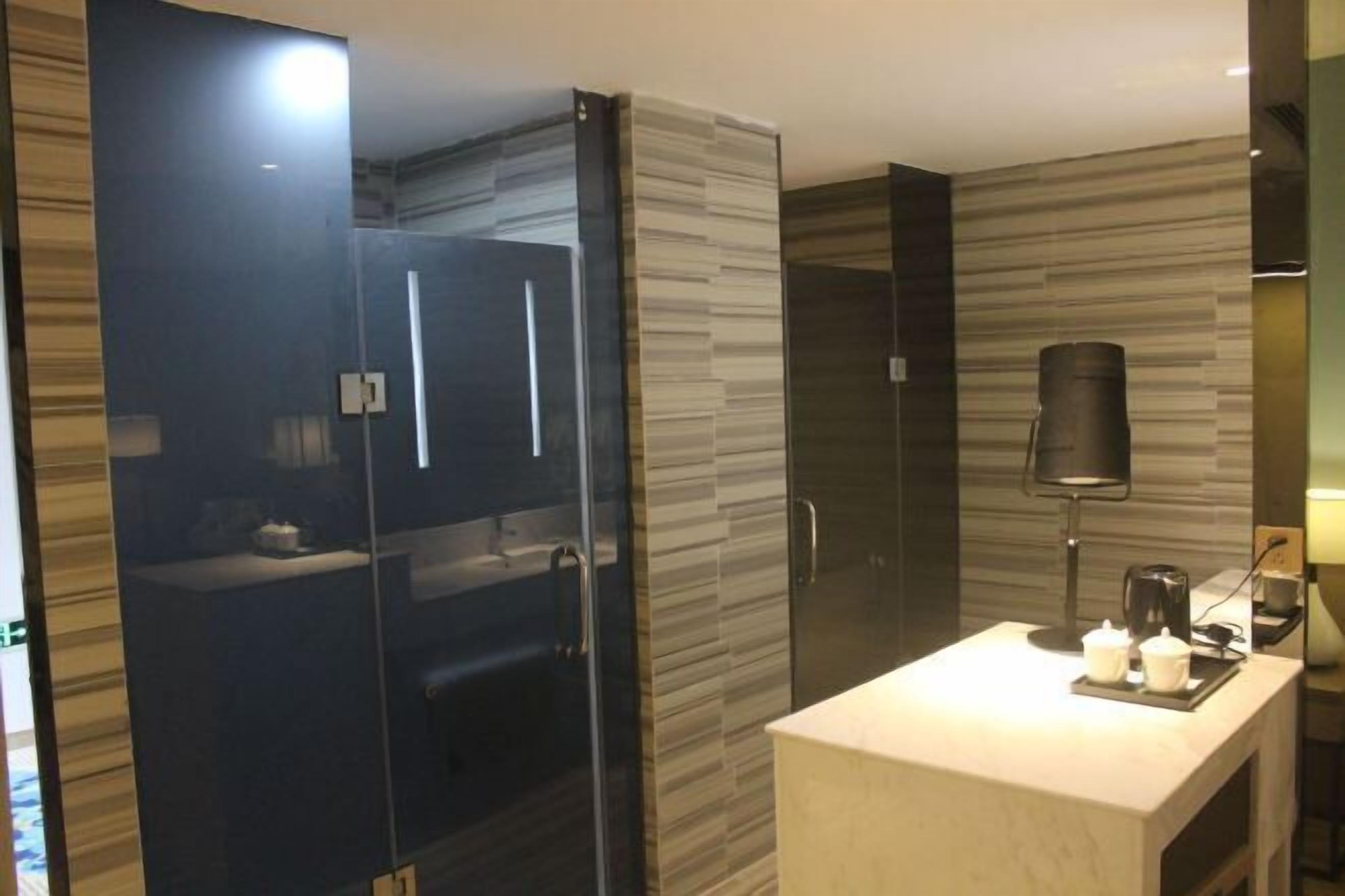 A modern bathroom with a glass shower enclosure, a vanity with a mirror, and a coffee maker on the counter.