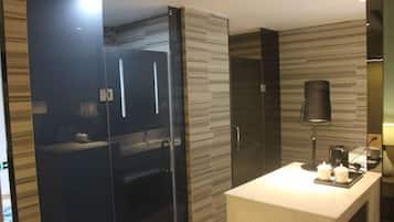 A modern bathroom with a glass shower enclosure, a vanity with a mirror, and a coffee maker on the counter.