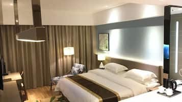 Une chambre d’hôtel comprenant un lit, des tables de chevet, un bureau, une chaise, une lampe, un tableau au mur et un téléviseur.