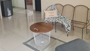 Ett vardagsrum med ett runt soffbord i trä, en mönstrad soffa och en färgstark, abstrakt tavla på väggen.
