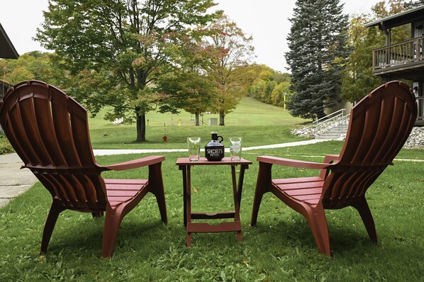 Two wooden Adirondack chairs with a small table between them, featuring two bottles and a coffee mug. - Schuss Mountain. 2 bedroom, 1.5 bath Sleeps 6. Pool Dog Friendly boat parking (Mancelona)