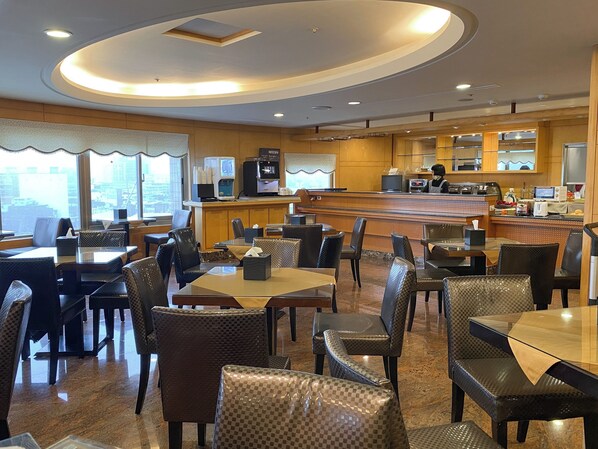 A restaurant with a bar area, seating arrangements, and a view of the cityscape through large windows.