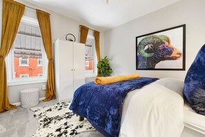 A bedroom with a bed, a wardrobe, a window with curtains, a plant, and a framed picture on the wall. - ★ HostWise Stays ★ 4 Blocks From UPMC Children's (Pittsburgh)