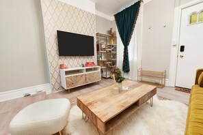 A living room with a wooden coffee table, white sofa, and a TV mounted on the wall. - ★ HostWise Stays ★ 4 Blocks From UPMC Children's (Pittsburgh)