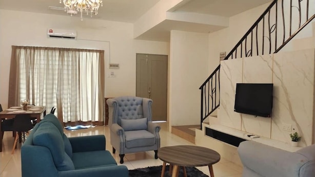 A living room with a chandelier, a TV mounted on the wall, a dining area with a table and chairs, and a staircase. - ZaraVip Homestay (Ipoh)