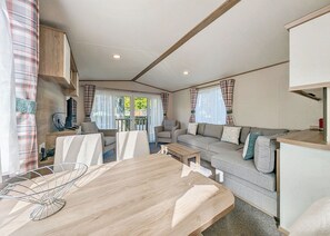 A caravan interior with a dining table, sofa, and kitchenette.