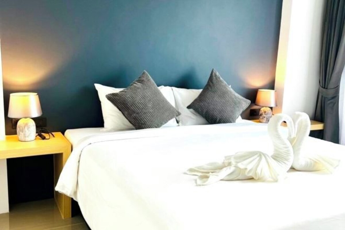 Un lit bien fait, avec des oreillers, une lampe de chevet et une serviette posée sur le lit.
