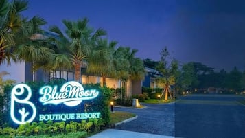 A sign for 'Blue Moon Boutique Resort' with a well-lit entrance and palm trees.