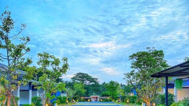 A hotel entrance with a paved pathway, trees, and buildings in the background. - Blue Moon Boutique Resort (Sichon)
