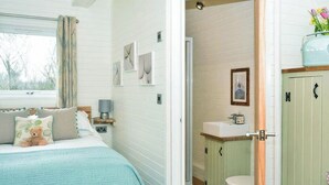 A bedroom with a bed, a bedside table, a lamp, and a window with curtains. - Imagine the fun of camping but with all the luxury comforts of a lodge holiday. (Hale)