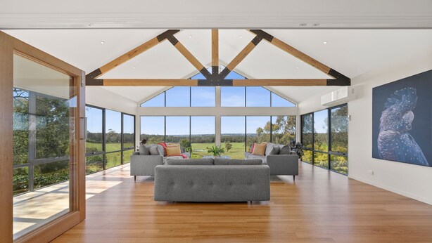 A spacious living room with large windows, a wooden ceiling, and a grey sofa. - Springhill Views-Country Retreat-sleeps12 (Spring Hill)