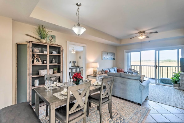 A dining area with a table set for four, a sofa, and a ceiling fan. - Breezy Darien Condo w/ Tranquil Marsh Views! (Darien)