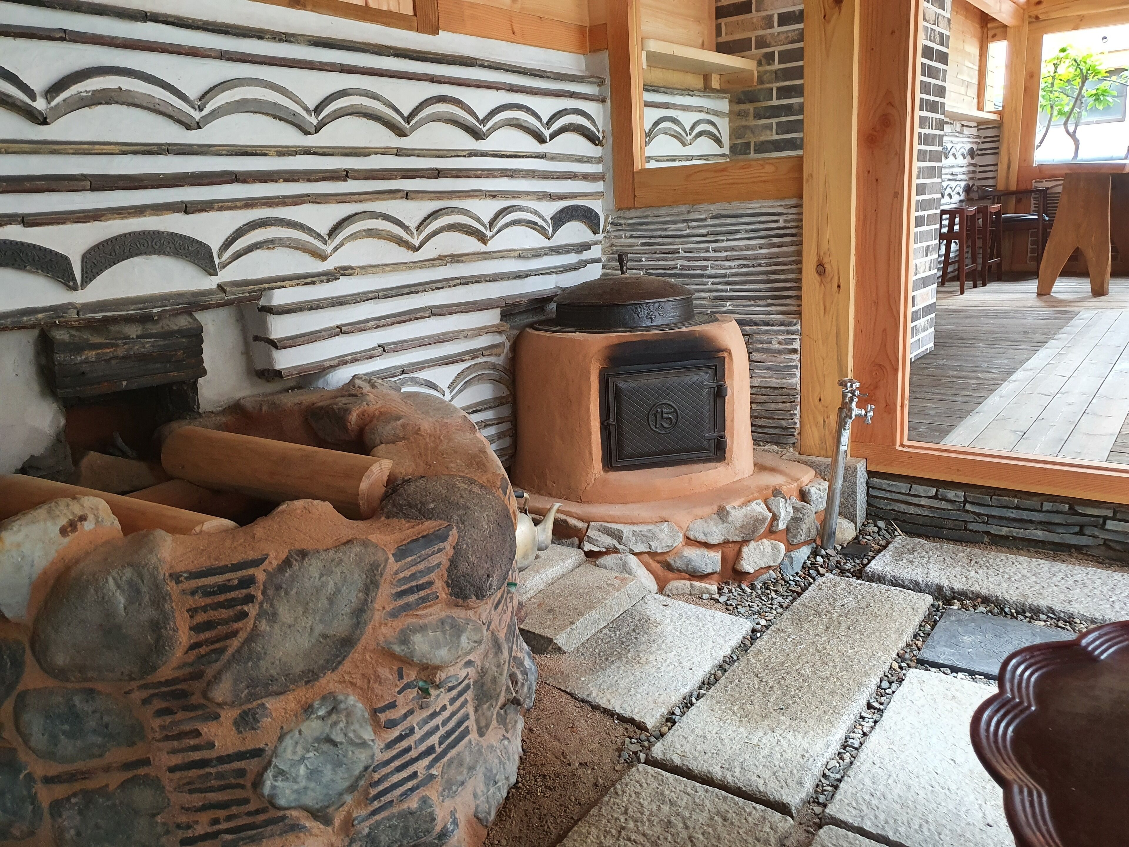 A rustic interior with a stone fireplace, wooden beams, and a stone bench.