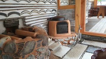 A rustic interior with a stone fireplace, wooden beams, and a stone bench.
