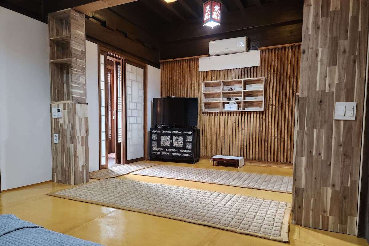 Quarto tradicional em estilo japonês, com tatames, televisão e armário de madeira.