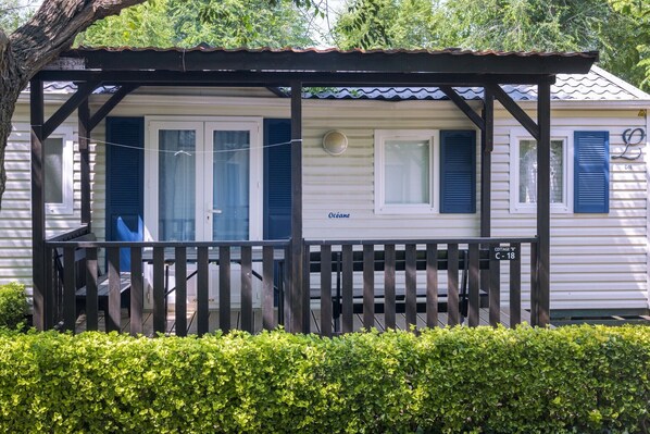 A mobile home with a porch, a small deck, and a sign indicating "Cottage C-18". - Cottage in Camping Solmar with Terrace (Blanes)