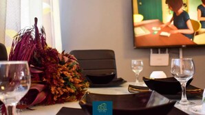 A conference room with a television screen, a decorative plant, and wine glasses on the table. - Cheerful 2-bed House in Mombasa (Mombasa)