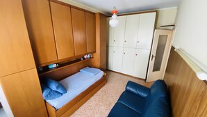 Ein gemütlicher Raum mit einem Bett, einer Couch und einem Kleiderschrank.