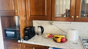 Eine Küche mit Holzausstattung, einer Mikrowelle, einer Kaffeemaschine und einer Obstschale auf der Arbeitsfläche.