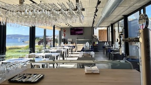 Ein Restaurant mit Meerblick, gedeckten Tischen und einer Bar.