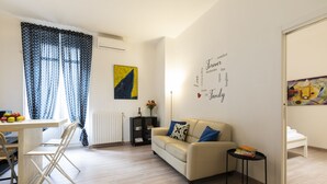 A modern living room with a sofa, a dining table with chairs, and a bookshelf. - notaMi - Cosy Home - Porta Romana MM3 (Milan)