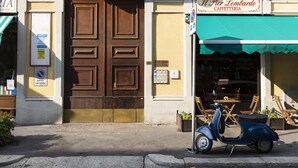 A building with a large wooden door, a cafe named "Il Pier Lombardo Caffetteria" with a green awning, and a parked scooter. - notaMi - Cosy Home - Porta Romana MM3 (Milan)