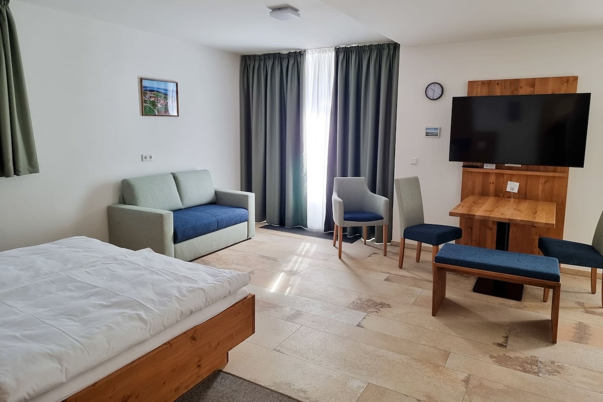 A hotel room with a bed, a sofa, a TV, and a small table.