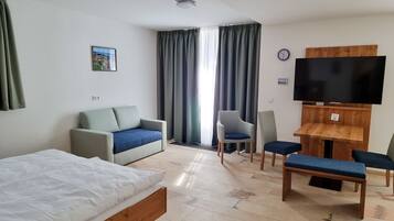 Une chambre d’hôtel avec un lit, un canapé, une télévision et une petite table.